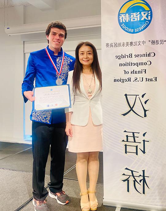 woman and man standing next to a sign, man holding award certificate